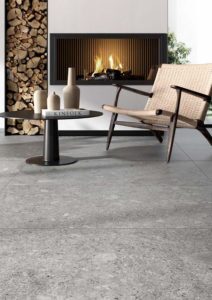 Keramische ceppo di gres in de woonkamer. Grote tegels 90x90cm op de vloer in combinatie met een scandinavisch interieur en haardvuur.