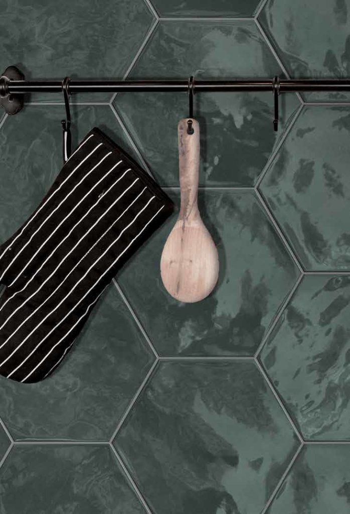 Kleine groene hexagon tegels als spatwand in de keuken.