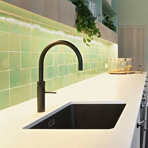 In deze tijdloze keuken werd er voor gekozen om pastel groene zelliges aan de spatwand te plaatsen. Hier met een witte voeg.