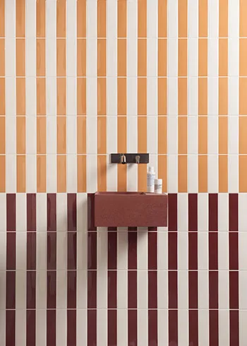 Striped tiles zijn de nieuwste tegeltrend waarbij tegels in strakke lijnen worden geplaatst. De combinatie van oker, bordeaux en wit zorgt voor een krachtig kleurenspel met warme uitstraling.