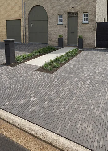 Moderne woning met oprit aangelegd in grijze kleiklinkers die zorgen voor een strakke en tijdloze uitstraling. Deze kleurvaste, slijtvaste gebakken klinkers zijn ideaal voor dagelijks gebruik rond de woning. Ontdek kleiklinkers en krijg persoonlijk advies bij Top Tegel 04 in Ieper, West-Vlaanderen.