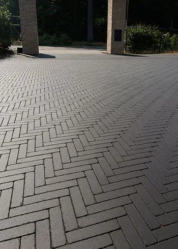 Oprit aangelegd in visgraatverband met duurzame kleiklinkers. Dit legpatroon zorgt voor extra stabiliteit en een krachtig lijnenspel, ideaal voor opritten met intensief gebruik. Kleurvaste gebakken klinkers te ontdekken met advies bij Top Tegel 04 in Ieper, West-Vlaanderen.
