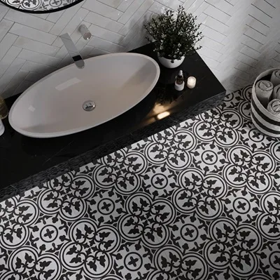 Revoir Paris La Madeleine Flavie Blanc patroontegel 20x20 cm in keramiek met klassiek bloemmotief in wit en zwart. Decoratieve vloertegel in cementtegel-look, geschikt voor vloer en wand in badkamer, keuken, toilet of inkomhal. Te bekijken in de toonzaal van Top Tegel 04 in Ieper.
