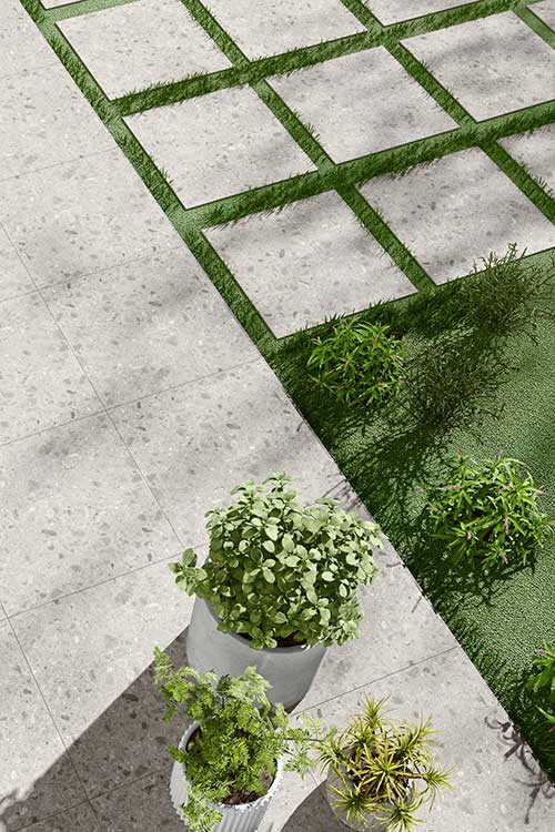 Licht grijze keramische terrastegels in ceppo look 60x60x2cm als stapstenen in het gras en terras.