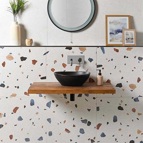 Terrazzo of granito tegels als vloer of wand. Hier werd een keramische witte terrazzo tegel met felle granulering in 60x120 tegen de badkamermuur geplaatst als accent. 
