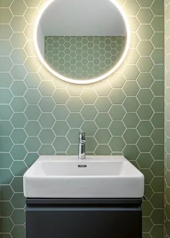 badkamer met groene hexagon mozaïektegels achter wastafel en ronde spiegel, kleine keramische tegels voor badkamerwand inspiratie, tegels vergelijkbaar met winckelmans topcer en pavigres te bekijken bij top tegel 04 ieper