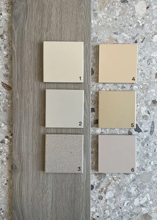 Overzicht van beige retro tegels 10x10 in verschillende tinten van Pavigres en Topcer op hout- en natuursteen ondergrond, te koop in toonzaal West-Vlaanderen tussen Ieper, Kortrijk en Roeselare met keuze uit meer dan 70 kleuren ongeglazuurde volkeramische full-body tegels